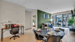 A modern dining area with a round table, black chairs, and a view of the street through large windows.