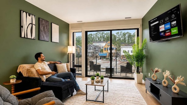 A modern living room with a sofa, a coffee table, and a TV mounted on the wall displaying various streaming services.