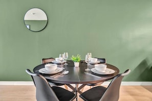 A dining area with a round table set for four, surrounded by chairs.