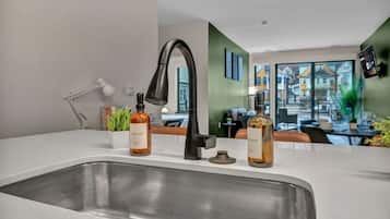 A modern kitchen with a stainless steel sink, two bottles of soap, a black faucet, and a white desk lamp.