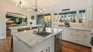 A modern kitchen with a marble island, stainless steel appliances, and pendant lighting. - Acadia Home with Hot Tub and Game Room (Mount Desert)