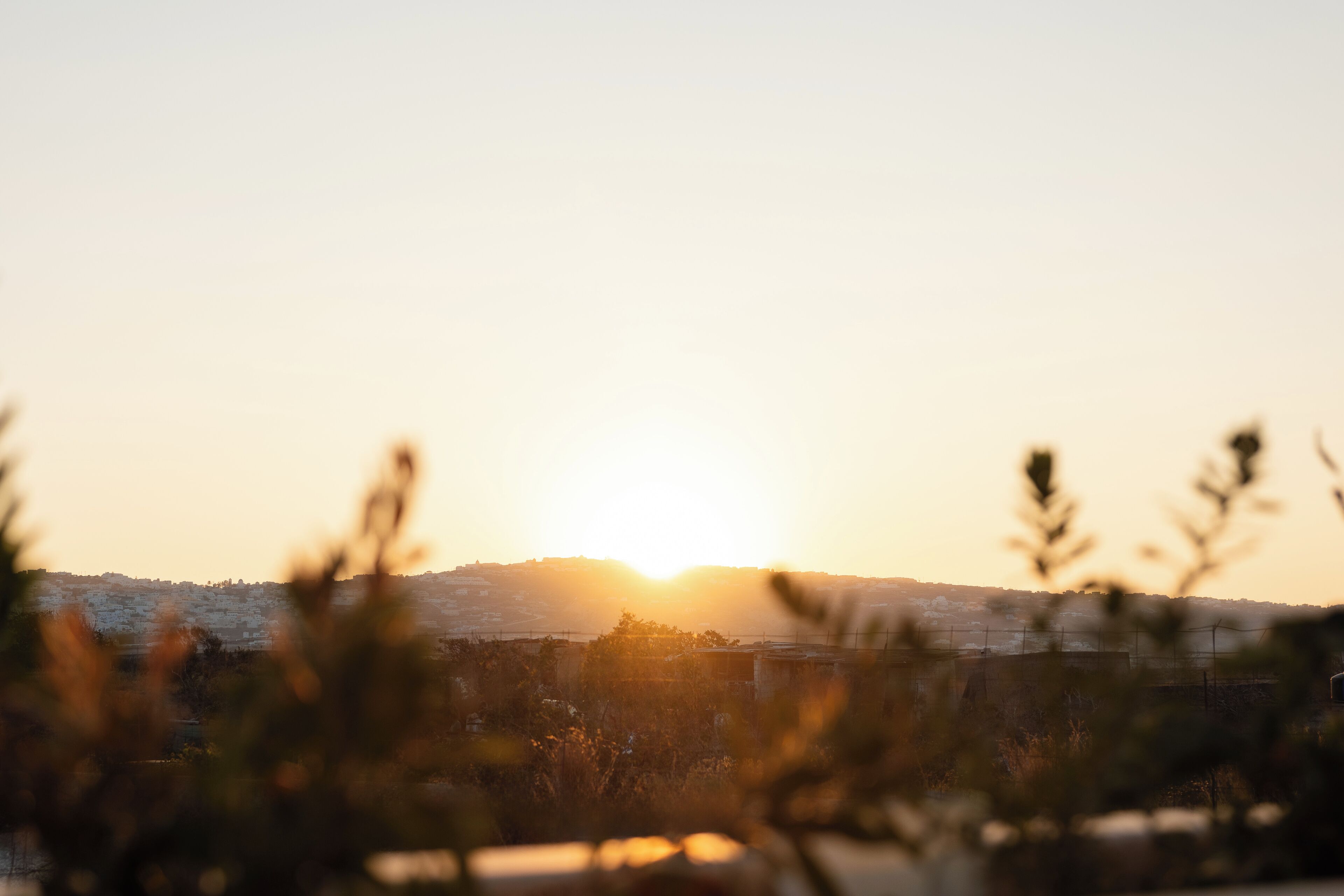 Ein Sonnenuntergang über einer Stadtlandschaft, mit Gebäuden in der Ferne.