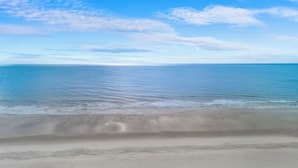 Une plage avec un ciel dégagé et une mer calme.
