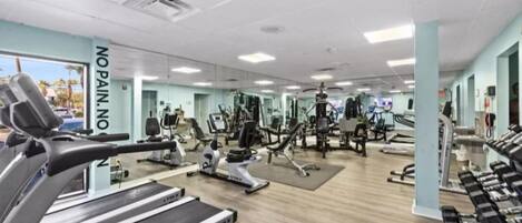 A gym with treadmills, weight machines, and a mirror wall.