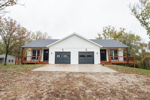 A two-story building with a central garage door and a covered porch on each side.
