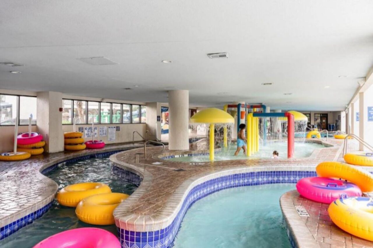 Ein Hallenbadbereich mit mehreren Wasserrutschen und aufblasbaren Ringen.