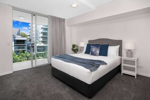 A modern bedroom with a large bed, a nightstand, a lamp, and a view of a balcony. - Stylish 2 BDR Apt Near QUT And RBWH With Parking (Kelvin Grove)