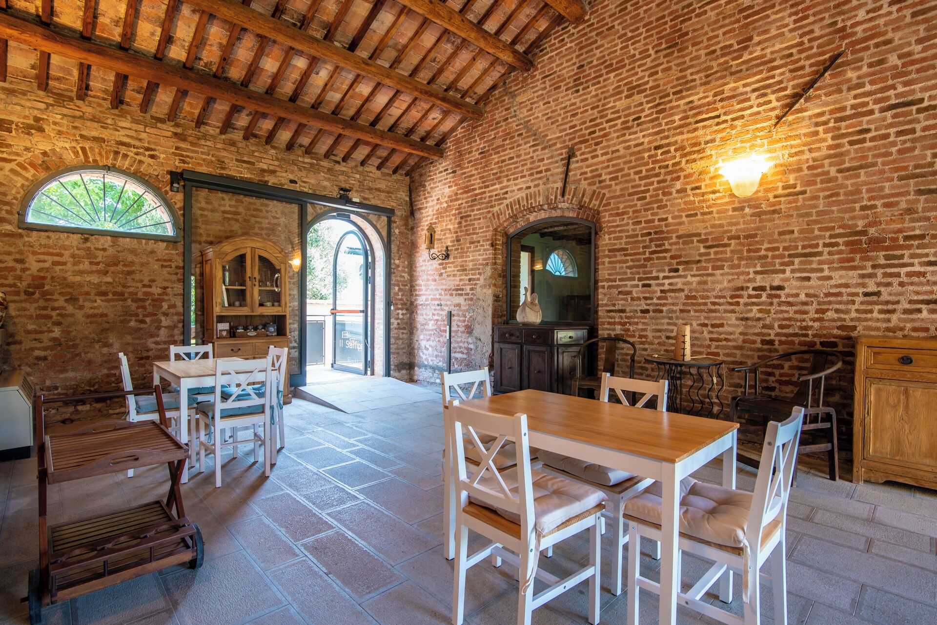 Un'area pranzo rustica con pareti in mattoni, travi in legno e una grande finestra.