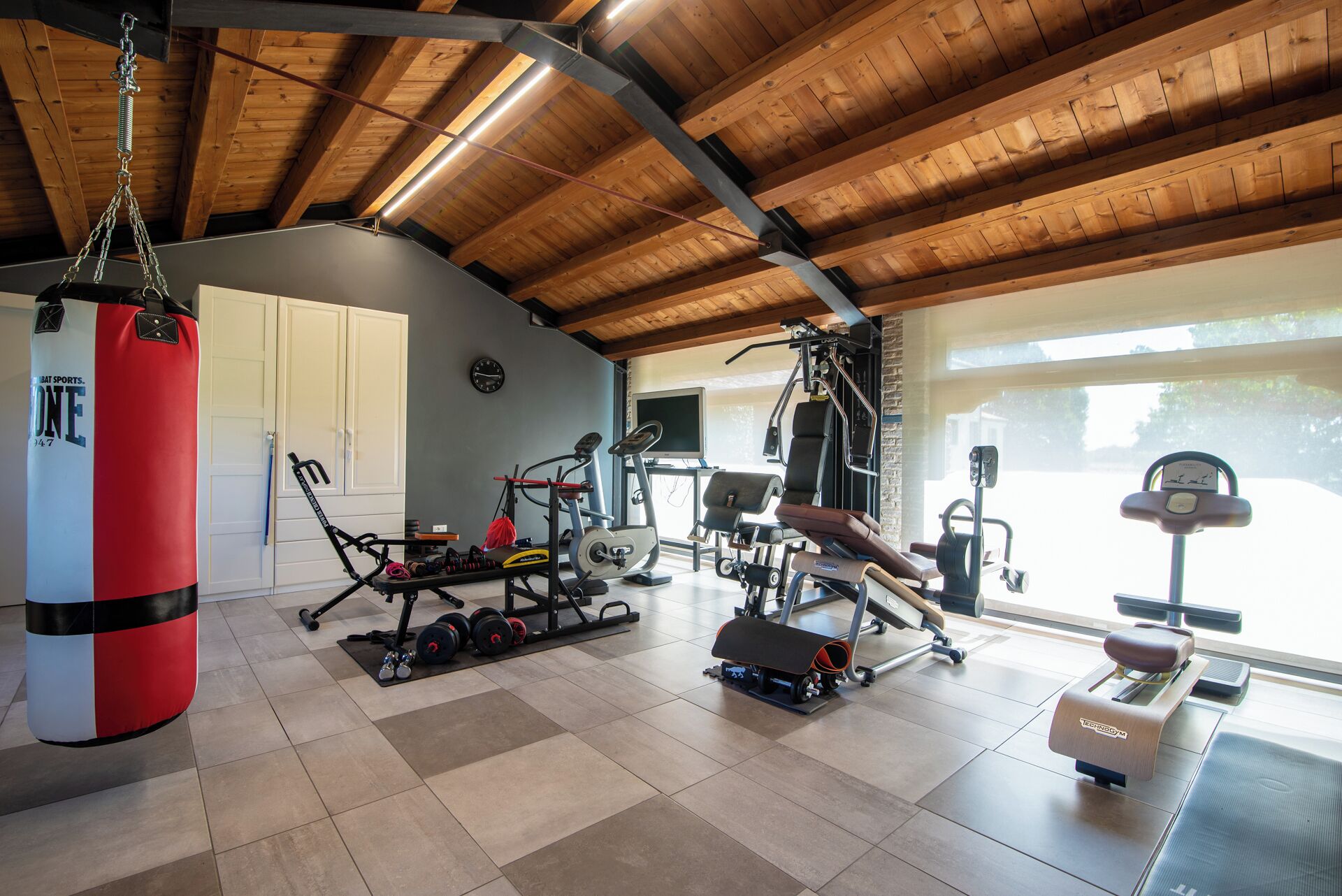 A gym with various exercise equipment, a punching bag, and a window with a view.