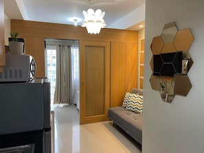 Ein modernes Wohnzimmer mit einer Couch, einem Wanddekor und einer Küchenzeile mit Geräten.