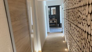 A hallway with wooden flooring and a wall covered in circular logs.