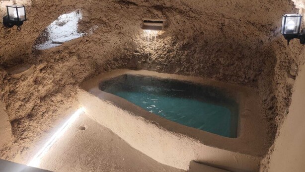 Ein Whirlpool inmitten von Sand mit zwei Wandleuchten.