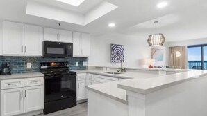 Una cocina moderna con armarios blancos, un horno negro y una isla grande.
