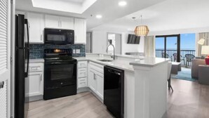 A modern kitchen with white cabinets, a black refrigerator, and a built-in microwave.