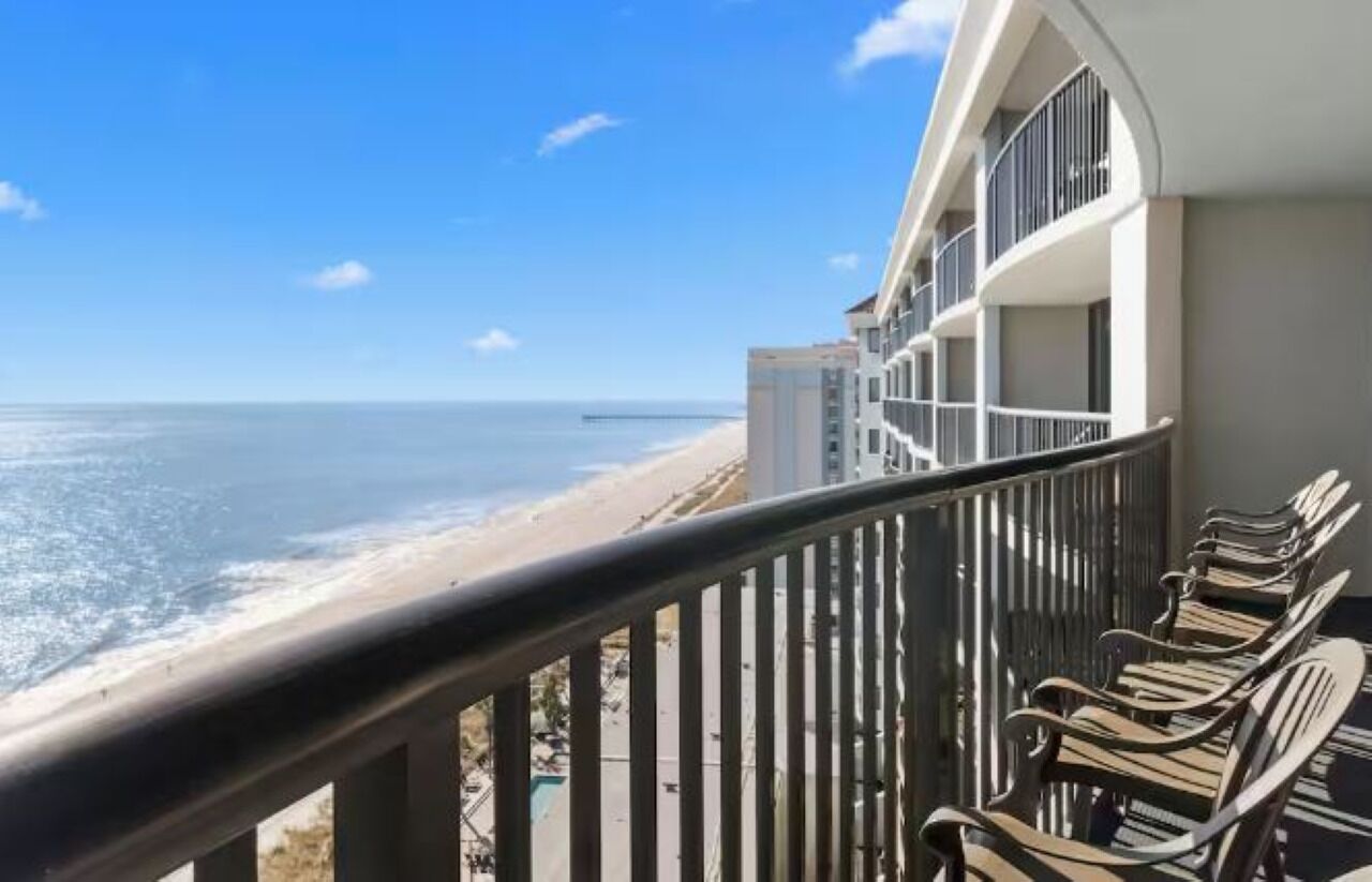 Un balcon avec vue sur la plage et l’océan.