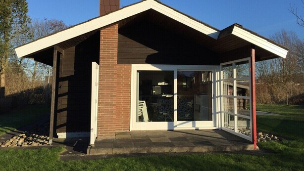 Een modern huis met een schuin dak, een bakstenen gevel en een overdekte veranda.