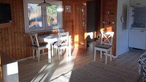 Een houten interieur met een eethoek, een keuken en een groot raam.