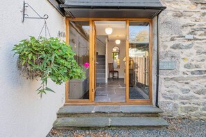 Une entrée en pierre, avec une porte en bois et des marches menant à un escalier.