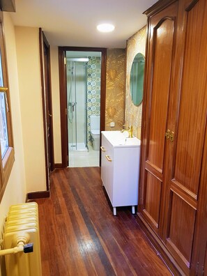 A bathroom with a wooden floor, a white sink, and a wooden wardrobe. - La Casa de Lorenzo, complete & practical accommodation. In Laguardia center! (Laguardia)