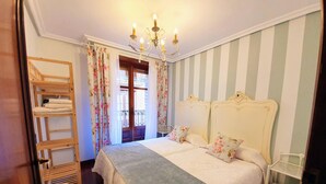 A bedroom with two beds, a chandelier, striped wallpaper, and a wooden ladder. - La Casa de Lorenzo, complete & practical accommodation. In Laguardia center! (Laguardia)