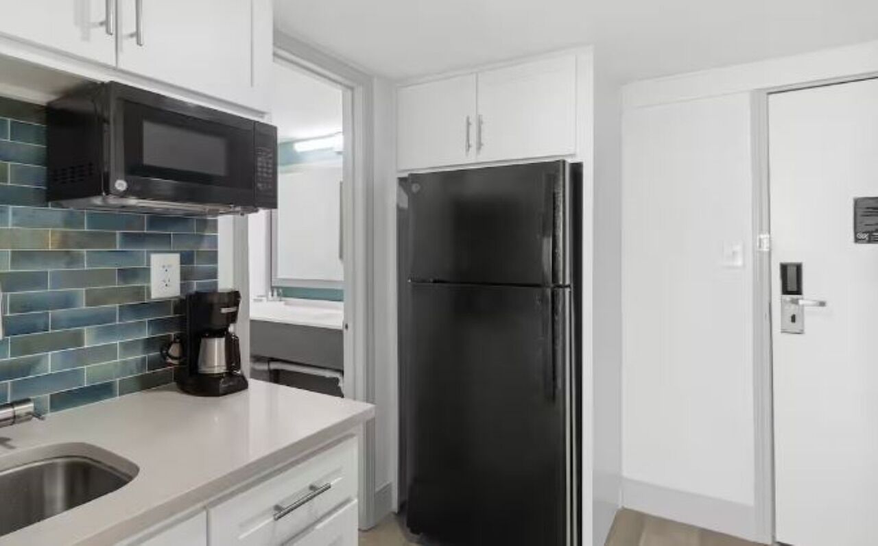 A modern kitchen with a black refrigerator, a microwave, and a coffee maker.