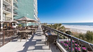 A balcony with outdoor seating and a view of the beach. - Modern Oceanfront Retreat l 4 Units | Free Parking | Indoor and Outdoor Pools (Myrtle Beach)