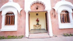 A building with a central entrance, flanked by two arched windows with wooden frames. - Palette Hotel and Resort LBS INT (Pindra)