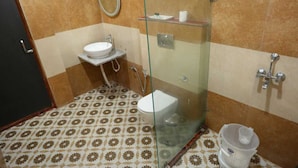 A bathroom with a glass shower enclosure, a white sink, and patterned floor tiles. - Palette Hotel and Resort LBS INT (Pindra)