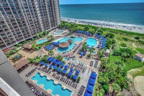 Un hotel con diverse piscine, una spiaggia e vista sull'oceano.