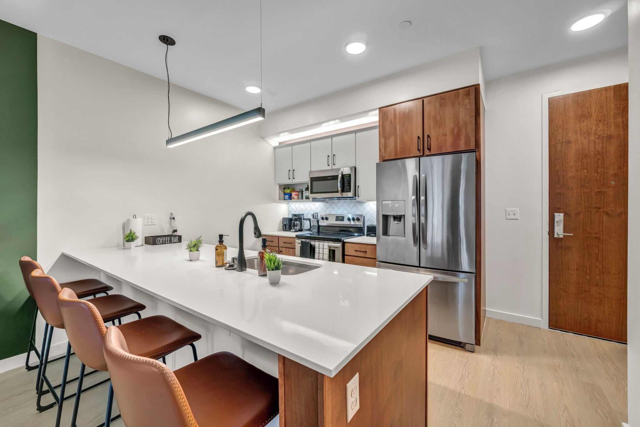 A modern kitchen with a central island, stainless steel appliances, and wooden cabinets.