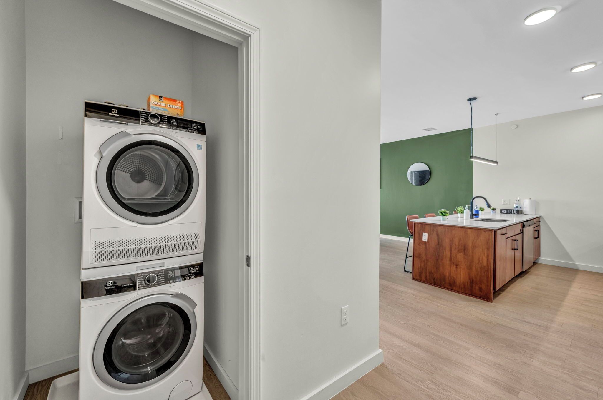 A laundry area with stacked washers and dryers, a wooden island with a sink, and a green accent wall.