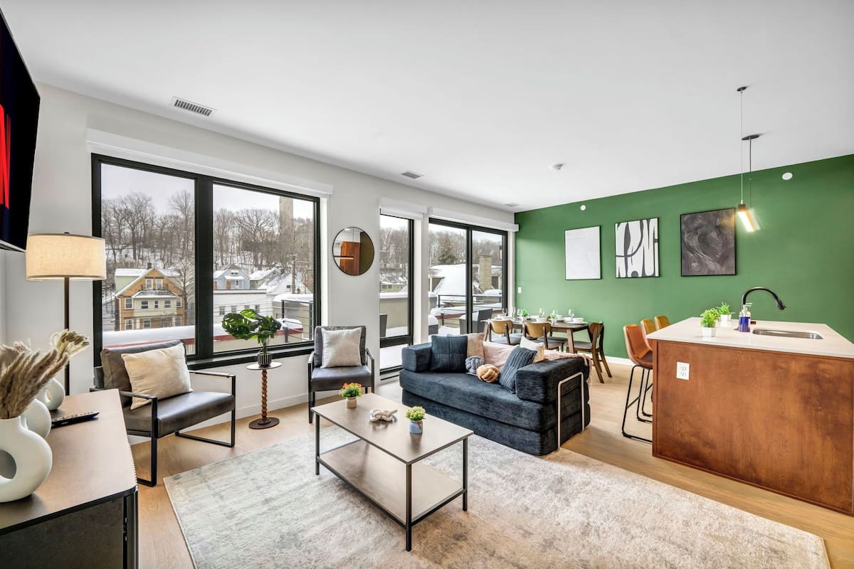 A modern living room with a sofa, coffee table, and a dining area with chairs and a table.