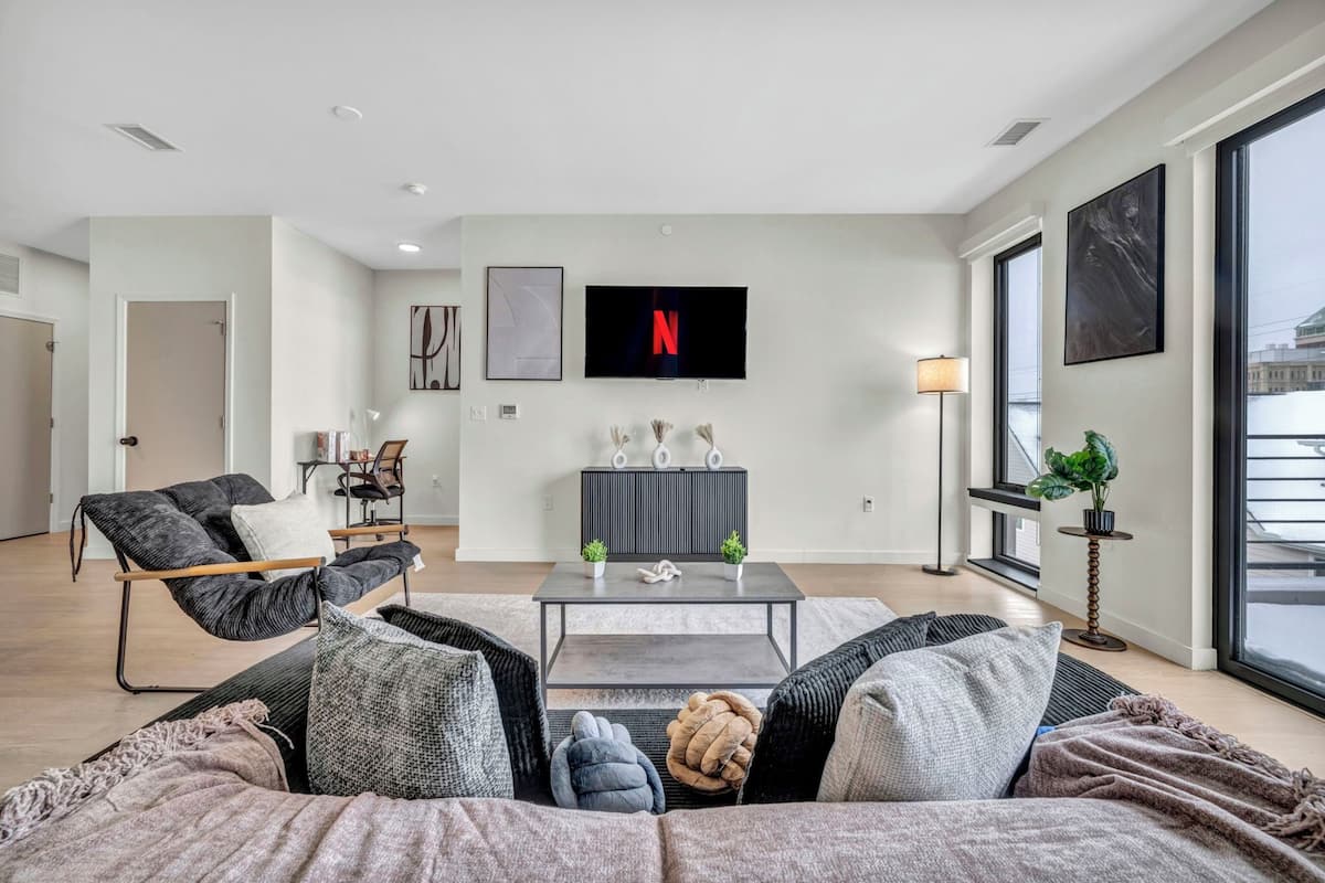 A modern living room with a sofa, coffee table, and a TV mounted on the wall.