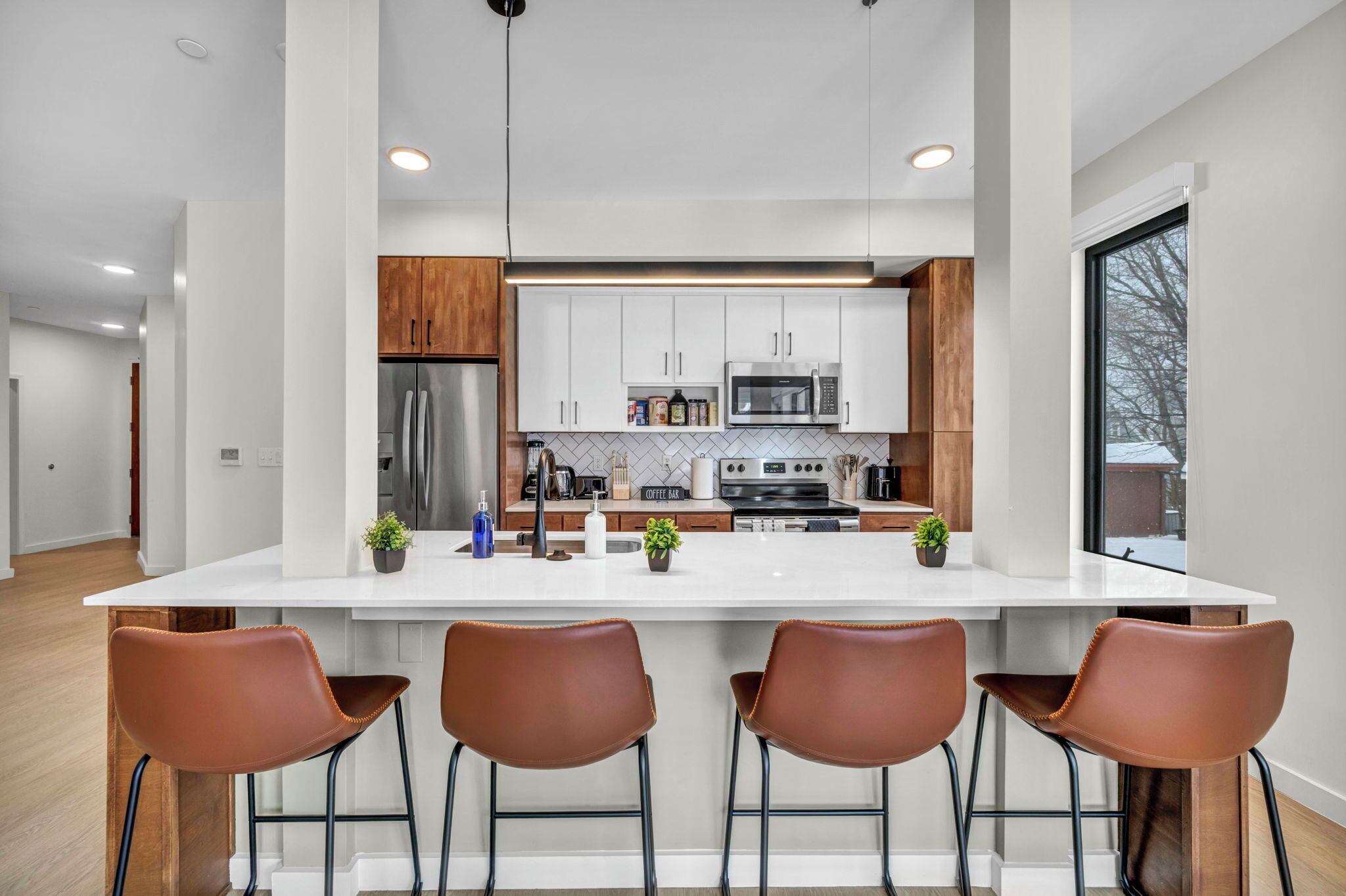 A modern kitchen with white cabinetry, stainless steel appliances, and a central island with bar stools.