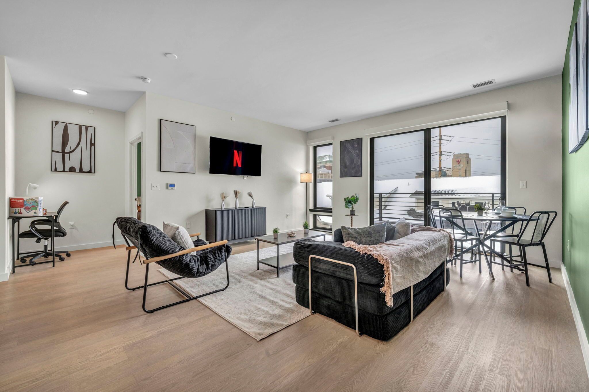 A modern living room with a sofa, armchair, dining table, and TV.