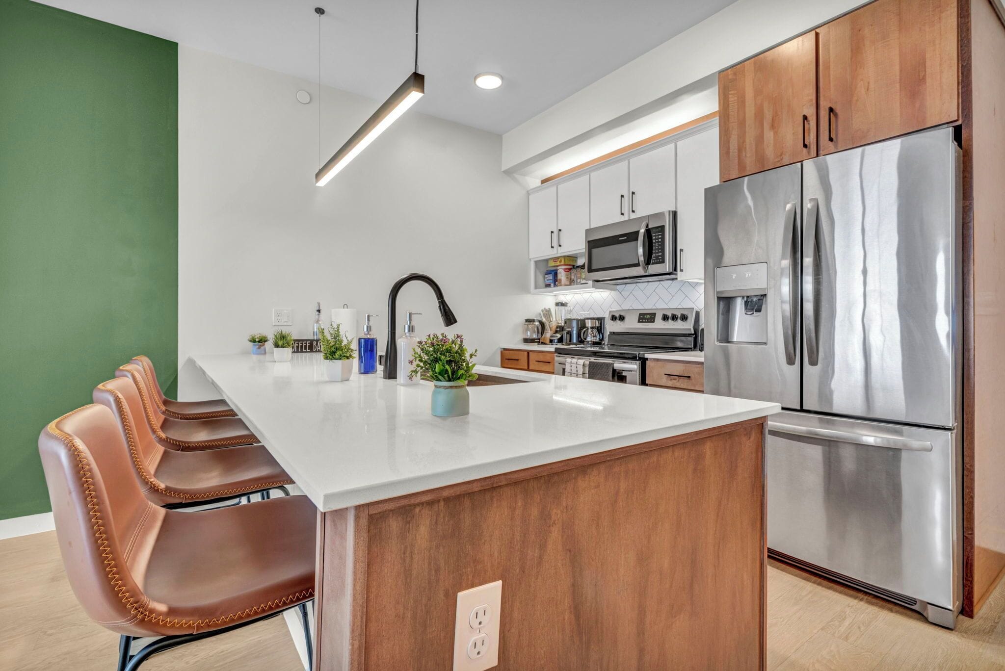 A modern kitchen with a central island, stainless steel appliances, and wooden cabinets.