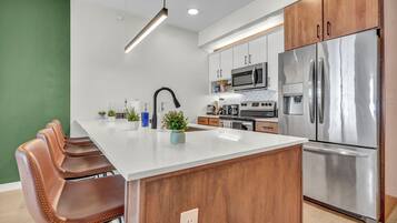 A modern kitchen with a central island, stainless steel appliances, and wooden cabinets.