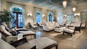 Un salon spacieux doté de plusieurs coins salon, de grandes fenêtres et d’élégants lustres.