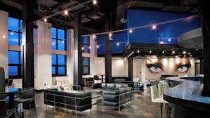 Un espace de détente moderne doté de hauts plafonds, de grandes fenêtres et d’un bar.