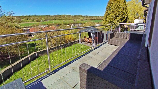 A balcony with a view of a green landscape, a covered seating area, and a metal railing. - Cosy holiday flat in a quiet location, close to Luxembourg and Trier (Ralingen)