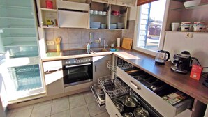 A compact kitchen with a built-in oven, a dishwasher, and a window providing natural light. - Cosy holiday flat in a quiet location, close to Luxembourg and Trier (Ralingen)