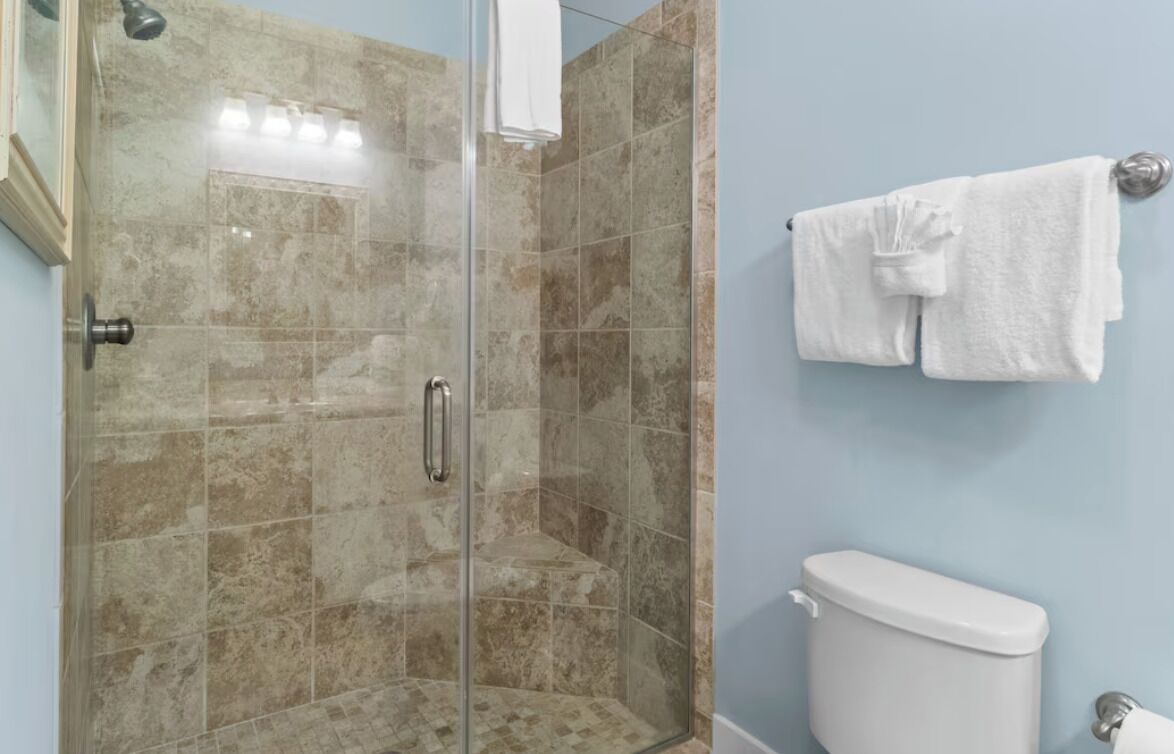 Un bagno con doccia vetrata, un water e un porta asciugamani con asciugamani.