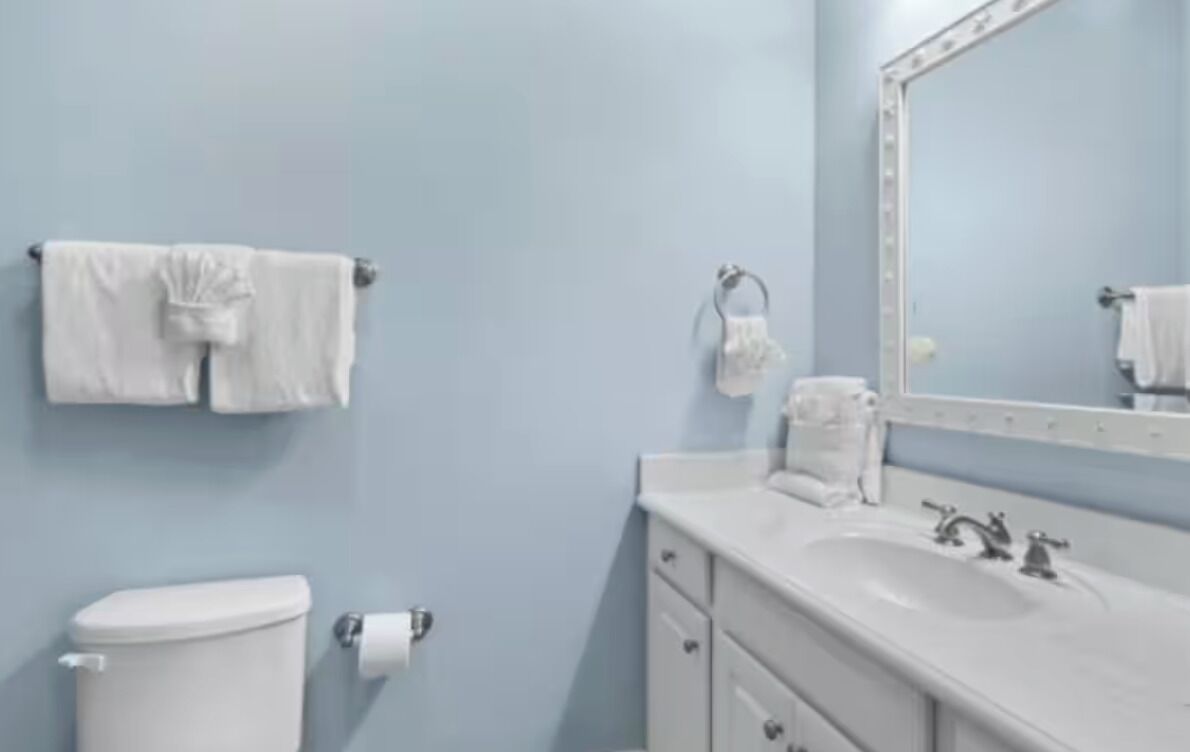Un bagno con il water, un lavandino e uno specchio.