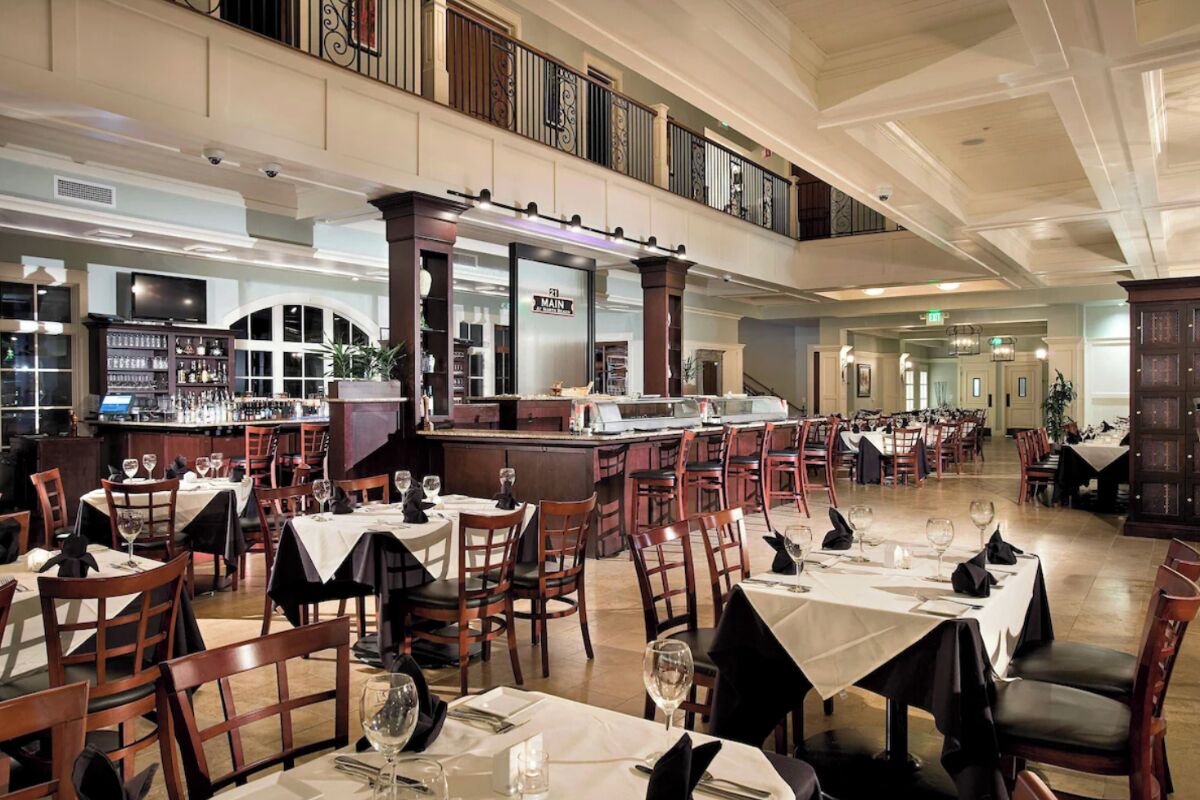 Ein geräumiges Restaurant mit mehreren Essbereichen, einer Bar und Blick auf die Stadtlandschaft.