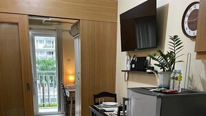 Et moderne køkken med indbygget køleskab, et spisebord med stole og et fjernsyn monteret på væggen.