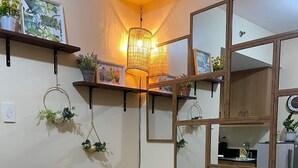 En hyggelig stue med en grøn sofa med et mønster, dekorative puder, vægmonterede hylder med planter og et spejl.