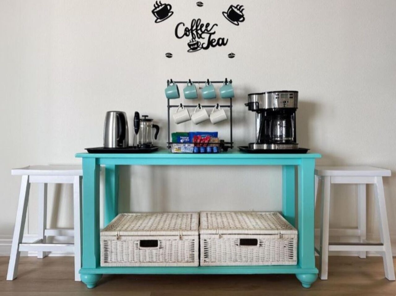 A teal coffee station with a coffee machine, mugs, and baskets.