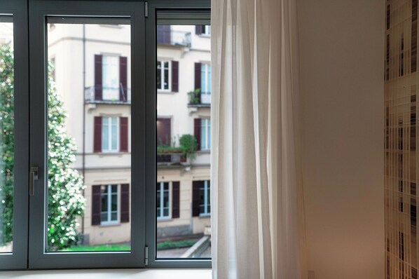 Ein Fenster mit Blick auf ein Gebäude mit Balkonen und Rollläden.