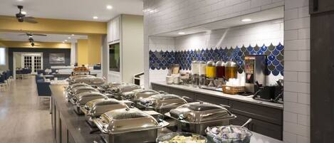 Uma disposição de buffet com várias estações de comida e uma área de estar.