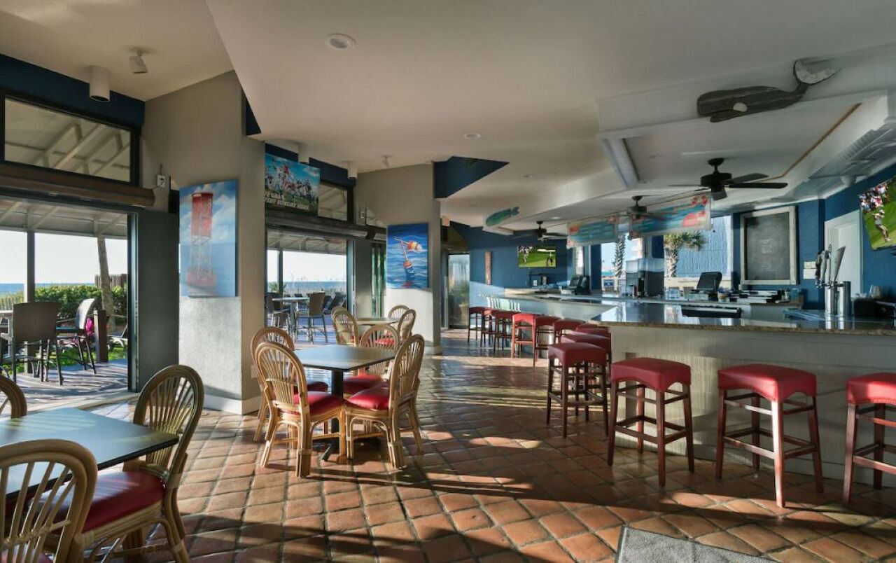 Un restaurante con terraza, una zona de bar y grandes ventanales que ofrecen vistas.